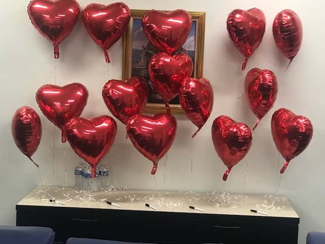 A collection of red, heart shaped helium balloons
