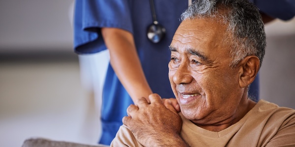 Caregiver holding hand of her senior patient and showing kindness while doing a checkup