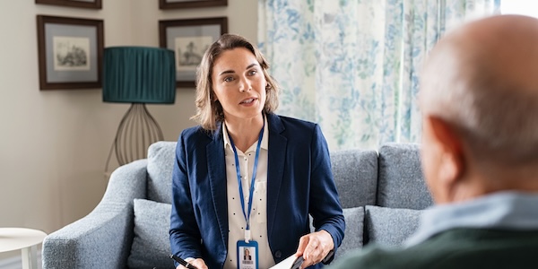 social worker talking to senior man and taking notes of health progress